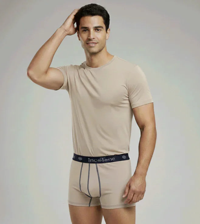 Man wearing beige underwear with a visible brand logo on a plain background